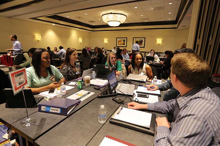 Students conversing around table during a conference session.